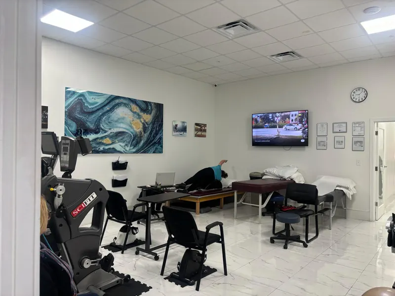 Sala principal de fisioterapia de All In One Specialty Health en Miami Gardens, con camillas de tratamiento, estaciones de ejercicio y una bicicleta SciFit